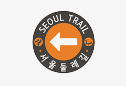 서울둘레길 방향을 가리키는 스티커형 안내판, 흰색 화살표와 함께 'Seoul Trail 서울둘레길'이라는 글씨가 표시됨