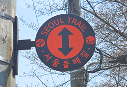 서울둘레길 방향을 가리키는 부착형 안내판, 위쪽 방향 화살표와 함께 'Seoul Trail 서울둘레길'이라는 글씨가 표시됨